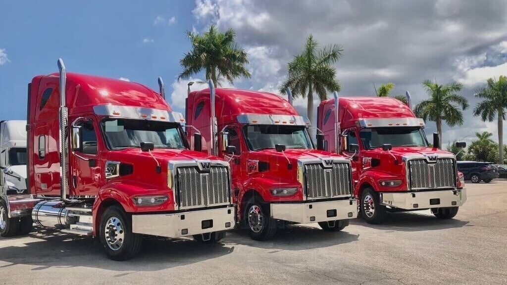 3 red Western Star 4900 sleeper trucks on a parking lot
